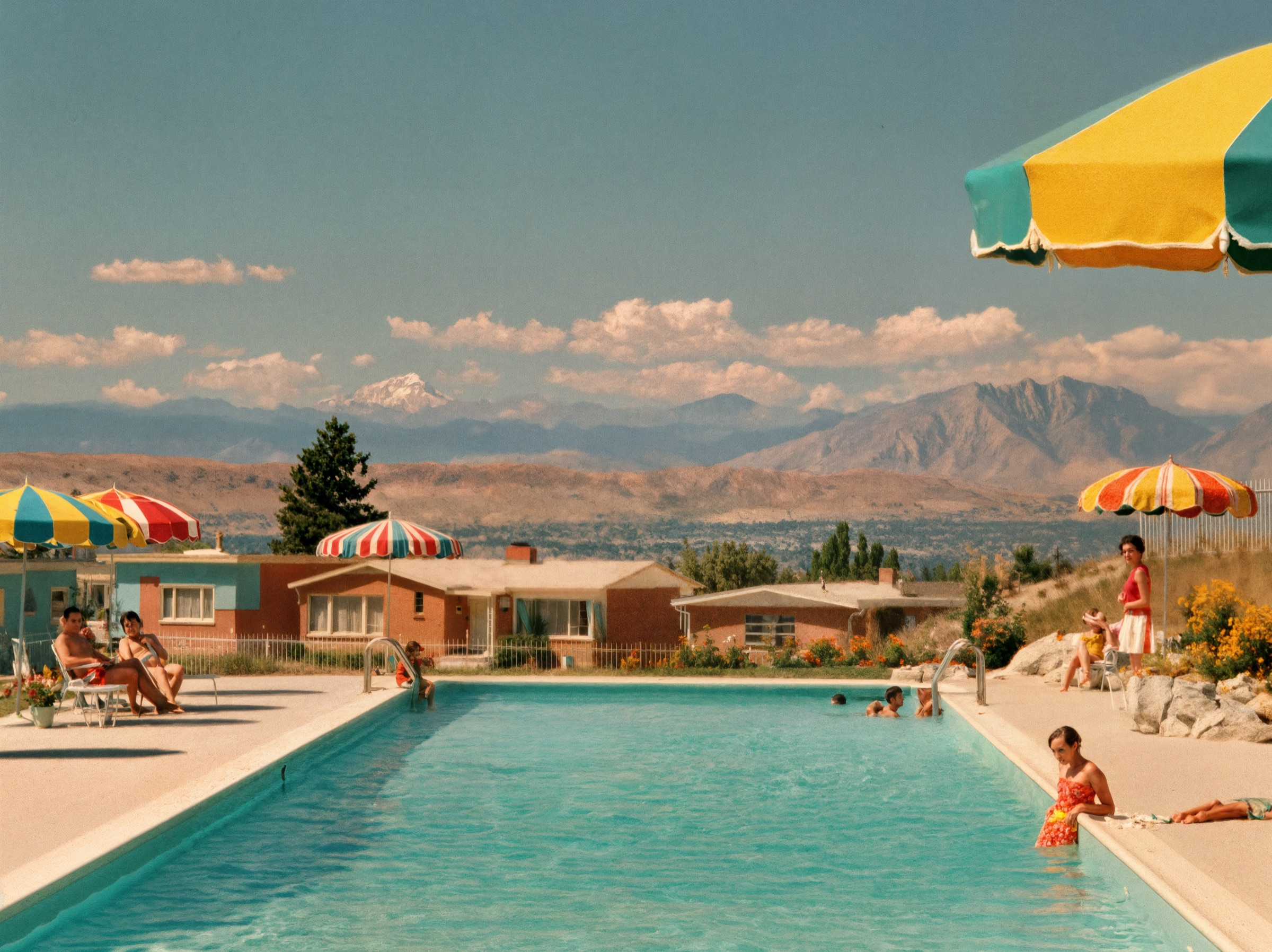 Community members relaxing poolside at a mid-century pool with the Rocky Mountains in the background